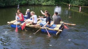 Eine Gruppe Floßbauer paddeln auf selbstgebautem Floß